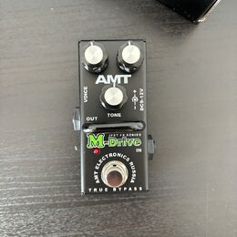 Černý efekt pedál s třemi bílými ovládacími knoflíky. Na horní části je bílé logo AMT a popisky VOICE, TONE a DC9-12V. Spodní část obsahuje zelený ná…