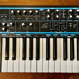 Černý analogový syntetizátor s klaviaturou a ovládacím panelem. Na levé straně je nápis novation BASS STATION II Analog Synthesizer. Panel obsahuje m…