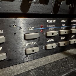 Detailní záběr na ovládací panel černého rackového efektového procesoru. Jsou vidět tlačítka s nápisy EDIT, BYPASS, STORE a OGRAM (část slova PROGRAM…