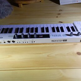 Bílá klaviatura s 37 klávesami. Na přední hraně je nápis KEYSTEP 37 a pod ním text CONTROLLER & SEQUENCER, v pravém rohu je logo (A.). Vlevo na horní…