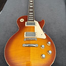 Elektrická kytara s trupem v barvě sunburst a viditnou strukturou dřeva. Nástroj má dva humbuckery, bílý plechtrpáč a čtyři zlaté ovládací knoflíky.…