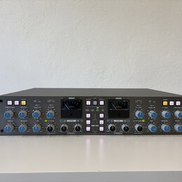Šedý rackový studiový kompresor s nápisy Solid State Logic vlevo a THE BUS+ vpravo. Přední panel obsahuje dva analogové VU metry, řadu regulačních kn…