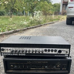 Dvě černé basové komba v rackovém provedení naskládaná na sebe. Horní zařízení má nápis BACKLINE 600, logo GK a text 900 WATT BASS AMPLIFIER. Spodní…