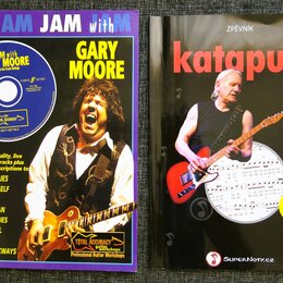 Fotografie zobrazuje dvě publikace: vzdělávací materiál pro kytaru a zpěvník. Vlevo je modrý sešit s nápisy JAM with GARY MOORE, Guitar Tablature a T…