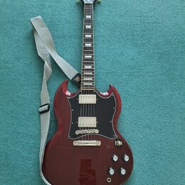 Elektrická kytara s červeným lakem a černým pickguardem. Na hlavě hmatníku je bílé logo Epiphone. Kytara má dva humbuckery, čtyři ovládací knoflíky a…