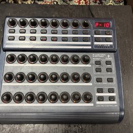 Modrý USB MIDI kontrolér s třemi řadami otočných knoflíků a řadou tlačítek. Na horním panelu je červený digitální displej s nápisem P-10 a nápisy VAL…