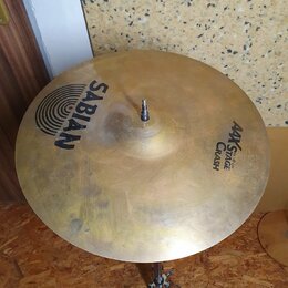 Zlatý činel typu crash umístěný na kovovém stojanu. Na povrchu jsou čitelné nápisy SABIAN a AAX STAGE CRASH 16"/40cm. Povrch vykazuje drobné nečistot…