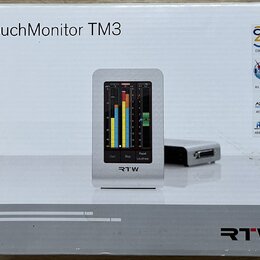 Krabice s nápisem TouchMonitor TM3 a logem RTW. Na obrázku je zobrazen stříbrný přístroj s displejem, který zobrazuje barevnéy měřiče úrovně a ovláda…