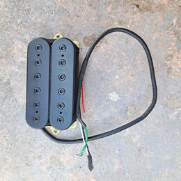 Černý humbucker s dvěma řadami po šesti pólech. Snímač je umístěn v žlutém plastovém rámečku a vede od něj černý kabel s odkrytými červeným, bílým a…