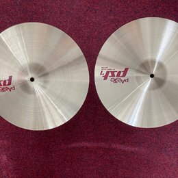 Dva kovové činely v přirozené zlatavé barvě s viditelným broušením povrchu. Na levém činele je nápis „paiste psX 14" HEAVY HI-HAT TOP“. Na pravém čin…