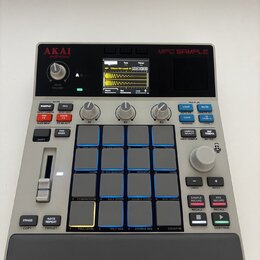 Šedý sampler MPC SAMPLE značky AKAI professional. Zařízení má v horní části displej s vizualizací zvukové vlny, ovládací knoflíky a v pravé části 16…