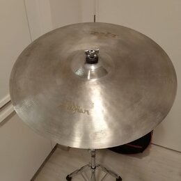 Stříbrný kovový činel umístěný na chromovaném stojanu. Na povrchu je viditelný nápis Zildjian a v horní části menší nápis K. Povrch vykazuje jemné šk…