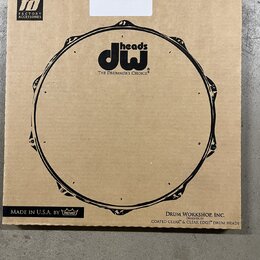 Kartonová krabice s černým potiskem stylizovaného bubnového obruče. Uprostřed je logo „dw heads“ a pod ním nápis „THE DRUMMER'S CHOICE®“. V levém hor…