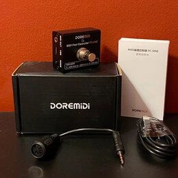 Černý MIDI pedál s nápisy DOREMIDI a MIDI Foot Controller FC-ONE. Vedle něj je černá krabice s bílým nápisem DOREMIDI a bílý manuál s textem MIDI脚踏控制…