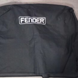 Černý textilní kryt nebo obal s bílým logem FENDER v horní části. Povrch materiálu vykazuje mírné pomačkání a vrásky. Předmět leží na světlé podlaze…