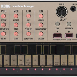 Stříbrošedý syntezátor KORG volca keys. Na horním panelu jsou ovládací prvky s nápisy VCO, VCF, LFO a EG, sekce DELAY a konektory MIDI IN, IN-SYNC-OU…