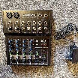 Černý kompaktní mixážní pult s nápisem Mix8 8-CHANNEL COMPACT MIXER a doprovodným logem. Zařízení obsahuje různé vstupy, potenciometry pro Gain, EQ,…