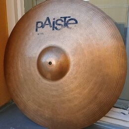 Kovový činel v bronzové barvě s viditelným koncentrickým rýhováním povrchu. V horní části je modré logo pAiste a pod ním menší nápis 20 RIDE. Povrch…