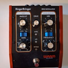 Černý efekt pedál s dřevěnými bočními stěnami. Na horní části je bílý nápis RingerBringer a RING MODULATOR. Přístroj obsahuje ovládací knoflíky s pop…