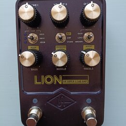 Tmavě hnědý kytarový pedál s nápisem LION 68 SUPER LEAD AMP a logem UA v kosočtverci. Horní řada obsahuje tři otočné knoflíky s popisky VOLUME I, VOL…