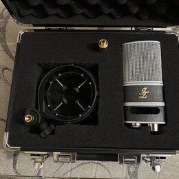 Kondenzátorový mikrofon stříbrné barvy s mřížkou a černý popfilter jsou umístěny v černé polstrované přepravní kufříku. Na těle mikrofonu je zlaté lo…