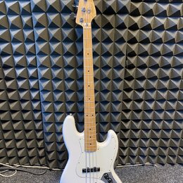 Bílá elektrická basová kytara s jasným dřevěným hmatníkem a hlavou. Na hlavě je viditelné logo Squier. Nástroj má čtyři struny, dva snímače a tři ovl…