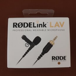 Fotografie znázorňuje bílé originální balení mikrofonu. Na krabici je uveden nápis RØDELink LAV a text PROFESSIONAL WEARABLE MICROPHONE, v pravém dol…