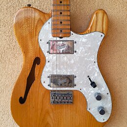 Polodupatá elektrická kytara s přírodním dřevěným povrchem a bílým perleťovým pickguardem. Na obou snímačích je viditelný nápis Gretsch. Nástroj má j…