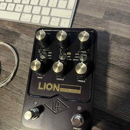 Černý kytarový předzesilovač s kovovým šasi a zlatými ovládacími knoflíky. Na předním panelu jsou nápisy LION 68 SUPER LEAD AMP, BASS, MIDDLE, TREBLE…