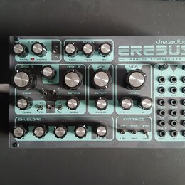 Analogový syntetizátor značky dre:adbox s modelem EREBUS. Zařízení má tyrkysový přední panel s mnoha ovládacími knoflíky a patch bayem s otvory pro k…