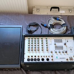Sada zvukové soustavy tvořená třemi černými reproduktory s mřížkami a mixážním pultem v přepravním kufru. Na pultu je nápis PORTABLE POWERED MIXER a…