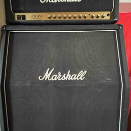 Kytarový kombozesilovač složený z hlavy a boxu značky Marshall. Na hlavě je bílé logo Marshall a nápis JCM 800 LEAD SERIES. Box má černou textilní př…