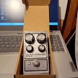 Stříbrný efekt pedál v kartonové krabici. Na přední straně je nápis POD GUNSLINGER MOSFET DISTORTION a čtyři ovládací knoflíky s popisky LOW, HIGH, O…