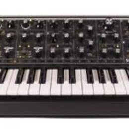 Černý synthesizér s dřevěnými bočními panely a bílo-černou klaviatura. Na ovládacím panelu jsou četné knofíky a přepínače, v pravé části je bílý nápi…