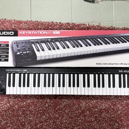 Fotografie zobrazuje černý klaviaturní kontrolér M-AUDIO KEYSTATION 61 MK3 a jeho původní kartonovou krabici. Na přístroji i na obalu je vidět značka…