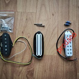 Tři elektrické snímače na kytaru v černé barvě. Jeden je s černým plastovým krytem a viditelnými póly, druhý má bílé plastové kryty v řadě a třetí je…