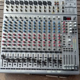 Stříbrný mixážní pult s nápisem EUROBACK UR244FX-PRO. Zařízení obsahuje několik vstupních kanálů s modrými a červenými otočnými knoflíky, posuvníky h…