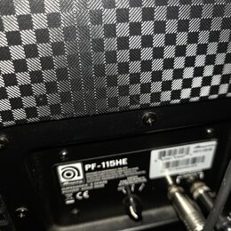 Detail zadní strany reproduktoru s černým šachovnicovým potahem. Na černé plošce je bílý nápis PF-115HE a logo s názvem Ampeg. Jsou zde uvedeny speci…