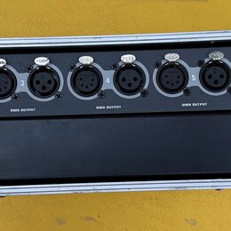 Černý rackový přístroj s nápisy dmx merger/splitter a dms 26. Na předním panelu se nachází šest skupin konektorů, z nichž každá obsahuje jeden vstup…