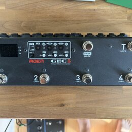 Černý kytarový spínací pedalboard s nápisy MOEN a GEC 5 Guitar Effect Commander. Zařízení má čtyři spodní spínače označené čísly 1, 2, 3 a 4 s doplňk…