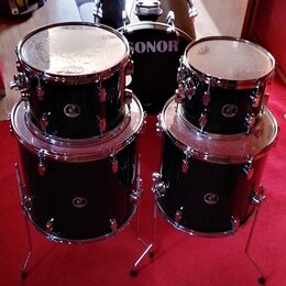 Sada černých bubnů s chromovaným kováním. Na basovém bubnu je bílý nápis SONOR a na ostatních bubnech jsou viditelné loga značky Sonor. Nástroje jsou…