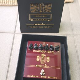 Červený efekt pedál v černé krabici. Na pedálu i na krabici je nápis COCKNEY RIOT, logo Kourbis a text HANDBUILT TUBE PEDALS. Pedál má čtyři černé ov…