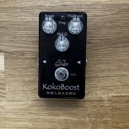 Černý kytarový efekt s nápisem KokoBoost RELOADED a logem Suhr. Na horní straně jsou tři ovládací knoflíky s popisky Boost, Freq a MidBoost (u prostř…