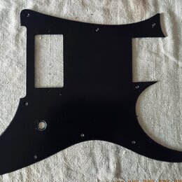 Černý plastový pickguard pro elektrickou kytaru s výřezem pro ovladače a otvorem pro kabel. Povrch je hladký a bez viditelných značek, log nebo nápis…