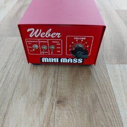 Červený hranatý přístroj s nápisem Weber a MINI MASS. Na přední straně jsou přepínače označené jako IMPEDANCE (8Ω, 16Ω, 4Ω), NORMAL a TREBLE (6db, 0d…