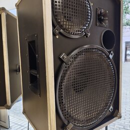 Černý reproduktor v hranatém kufrovém provedení s kovovými hranami. Přední strana obsahuje dva reproduktory chráněné mřížkami a jeden menší tubový re…