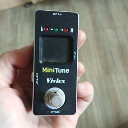 Černý kytarový ladič v kompaktním kovovém provedení. Na přední straně je displej, tři kontrolky a nápisy MiniTune a Vivlex. V horní části je označení…