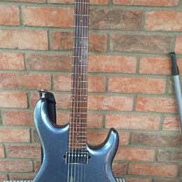 Modře metallic elektrická kytara s hnědým hmatníkem a dřevěnou hlavou. Na hlavě je svisle napsaný nápis Ibanez. Kytara má jeden humbucker u kobylky,…