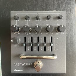 Šedý kytarový efekt s nápisy PENTATONE EQUALIZER a logem Ibanez. Zařízení obsahuje pět otočných knoflíků v horní části, pět knoflíků s označením frek…