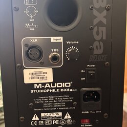 Zadní strana černého studiového monitoru. Je na něm vidět logo M-AUDIO a název modelu STUDIOPHILE BX5a DELUXE, v horní části je velký nápis BX5a DELU…